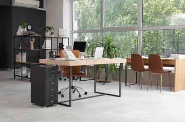 Masaları, raf birimleri ve palmiye ağaçları olan modern ofisin içi