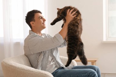 Evdeki kanepede oturan sevimli kedili genç adam.