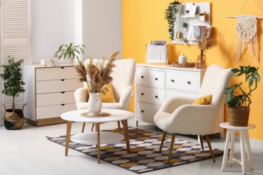 Beyaz kanepeli şık bir oturma odası, çekmeceler, sehpa, yumuşak koltuklar ve tahta tahtalar.