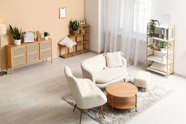 Beyaz kanepesi, koltuğu ve ahşap masası olan şık bir oturma odası.