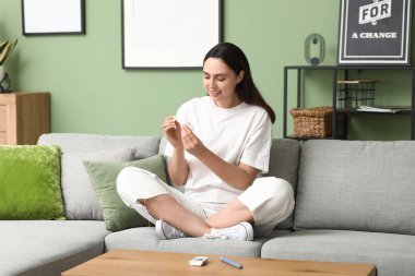 Şeker hastası genç bir kadın evdeki kanepede tükenmez kalem kullanıyor.