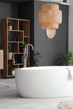 Küvet ve ahşap raf ünitesi ve modern banyoda ev bitkileri.