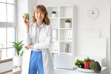 Ofisinde elma olan kadın beslenme uzmanı.