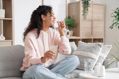 Genç Afro-Amerikalı kadın evde balık yağı alıyor.