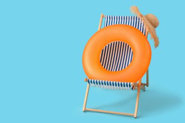 Mavi arka planda şişirilebilir halka ve güverte sandalyesi. Seyahat kavramı