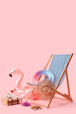 Şişirilebilir halkalar, güverte sandalyesi ve içinde hindistan cevizi olan bavul ve pembe arka planda kokteyl. Seyahat kavramı