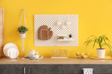 Siyah tezgahları ve sarı duvarın yanındaki tahta tahtaları olan şık bir mutfak.