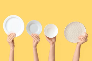 Sarı arkaplanda boş tabakları tutan eller