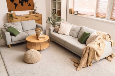 Beyaz duvarda rahat kanepeler, puf, masa ve dünya haritası olan oturma odasının içinde.