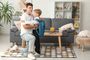 Baba, küçük oğluna sırt çantasıyla sarılıyor.