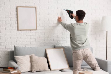 Oturma odasında, arka manzara için duvarı delen genç adam.