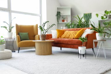 Yeşil çiçekleri, kanepesi ve koltuğu olan bir oturma odası.