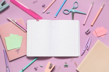 Leylak arka planında farklı kırtasiye malzemesi olan boş bir defter