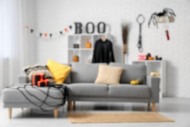 Cadılar Bayramı için dekore edilmiş şık oturma odasının içinde kanepe, raf ünitesi ve hediye kutuları var. Bulanık görünüm