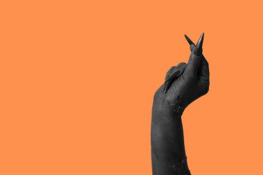 Cadının kara eli turuncu arka planda kalp hareketi gösteriyor. Cadılar Bayramı