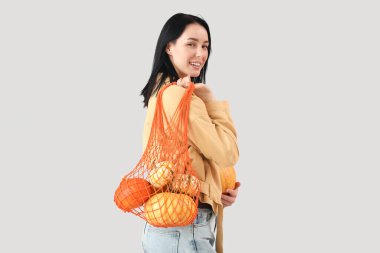 Gri arkaplanda bir sürü balkabağı olan güzel, mutlu bir kadın.