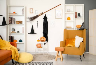 Cadılar Bayramı için dekore edilmiş oturma odasının içinde koltuk, raf üniteleri ve cadı şapkaları var.