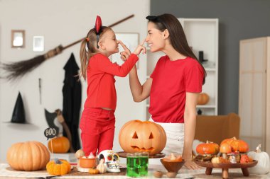 Mutlu anne ve küçük kızı Cadılar Bayramı için giyinmiş birbirlerinin burunlarına dokunuyorlar.