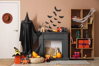 İçinde şömine, Cadılar Bayramı süslemeleri ve hediye kutuları olan festival salonu.