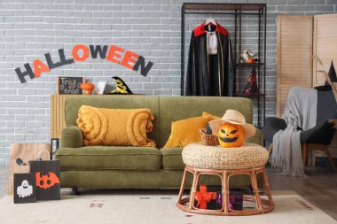 Cadılar Bayramı için dekore edilmiş modern oturma odasının içinde alışveriş torbaları, hediye kutuları ve balkabağı var.