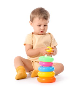 Beyaz arka planda oyuncak piramidiyle oynayan güzel bir kız bebek.