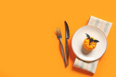 Turuncu arka planda Cadılar Bayramı kutlaması için taze balkabağı ve kağıt yarasayla güzel bir masa.