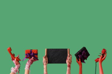 Anneciğim, zombi ve şeytan elli hediye kutuları, telefonlar ve yeşil arka planda boş karatahta. Cadılar Bayramı