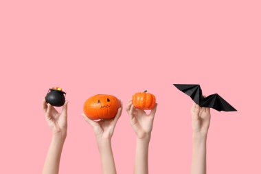 Esrarlı kadın eller, balkabakları ve pembe arka planda kağıt yarasa. Cadılar Bayramı