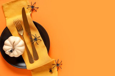 Turuncu arka planda örümcekler ve balkabağıyla Cadılar Bayramı kutlaması için şenlik masası.