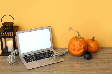 Cadılar Bayramı kutlamaları için dekore edilmiş şık ofis içlerinde dizüstü bilgisayarı, balkabağı ve feneri olan bir işyeri.