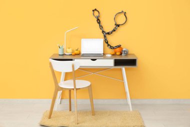 Cadılar Bayramı kutlamaları için dekore edilmiş şık ofis içinde dizüstü bilgisayarı, kabağı ve zinciri olan bir çalışma yeri.