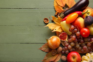 Farklı taze sebzeler, meyveler ve yeşil ahşap arka planda sonbahar yaprakları olan bir pano. Hasat festivali