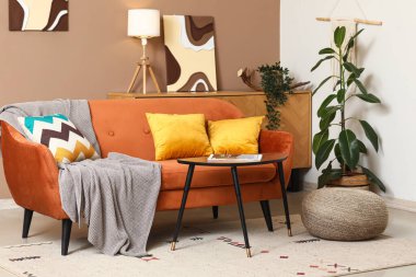 Turuncu kanepeli, kahve masalı ve çiçekli şık bir oda.