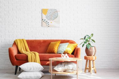 Kahverengi kanepeli, rahat battaniyeli, yastıklı ve kahve masalı şık bir oturma odası.