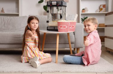 Evde elinde patlamış mısır makinesi olan küçük çocuklar onay veriyor.