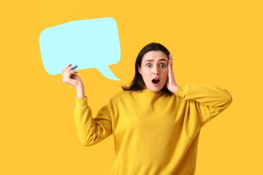 Sarı arka planda boş konuşma balonuyla şok olmuş genç bir kadın.