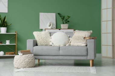 Oturma odasının içinde kanepe ve yeşil duvarın yanında kitaplar var.