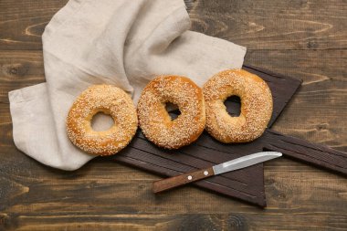 Tahta arka planda susam tohumlu lezzetli simit kesme tahtası