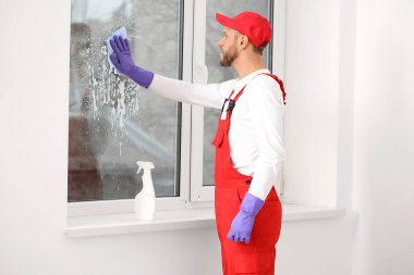 Erkek işçi odada cam yıkıyor.