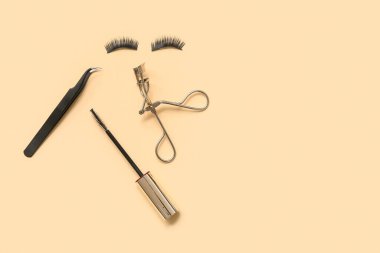 Takma kirpik, cımbız ve bej arka planda bigudi olan maskara fırçası.