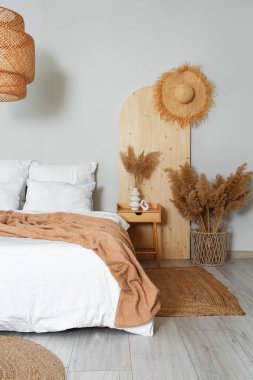 Şık bir yatak odası, rahat bir yatak odası, komodin ve otlar.