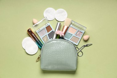 Pamuk yastıklı kompozisyon, kozmetik çanta ve yeşil arka planda makyaj ürünleri