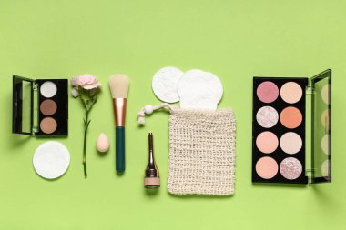 Pamuk pedlerle, çiçeklerle, makyaj ürünleriyle ve yeşil arka planda fırçayla kompozisyon