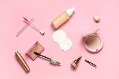 Pamuk yastıklı kompozisyon ve pembe arka planda farklı makyaj ürünleri