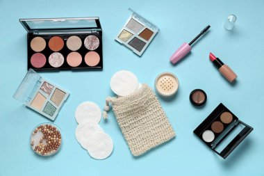 Mavi arka planda pamuk pedleri, çanta ve makyaj ürünleri ile kompozisyon
