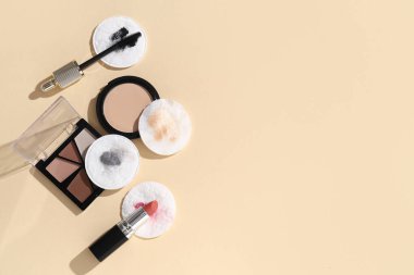Kirli pamuk pedleri ve bej arka planda farklı kozmetik ürünleri olan kompozisyon