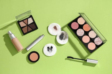 Yeşil arka planda kirli pamuk pedleri ve farklı kozmetik ürünleri olan kompozisyon