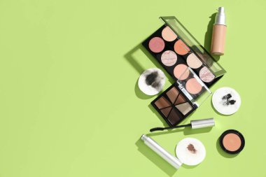 Yeşil arka planda kirli pamuk pedleri ve farklı kozmetik ürünleri olan kompozisyon