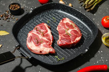 Taze çiğ biftekli tava ve siyah arka planda farklı baharatlar, yakın plan.