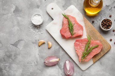 Taze çiğ biftek ve gri arka planda farklı baharatlar olan bir pano.